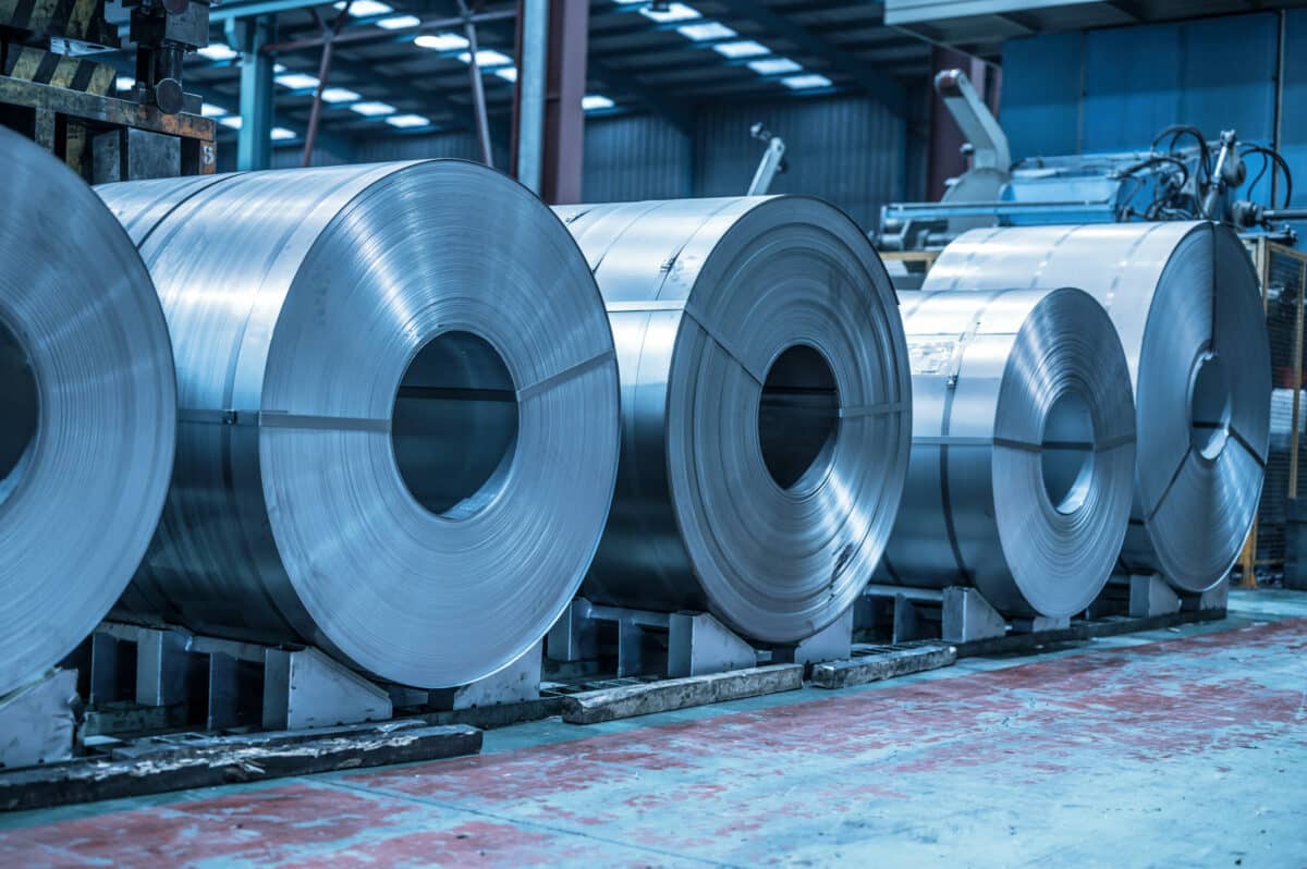 Industrial background. Big size steel coil stored inside industrial warehouse, blue toned image .